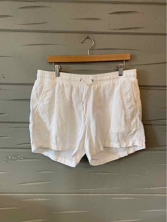White casual shorts with button closure, front pockets, and relaxed fit on wooden hanger.