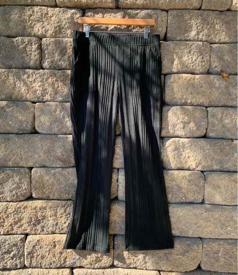 Black ribbed knit lounge pants with a straight-leg fit hanging on a wooden hanger.