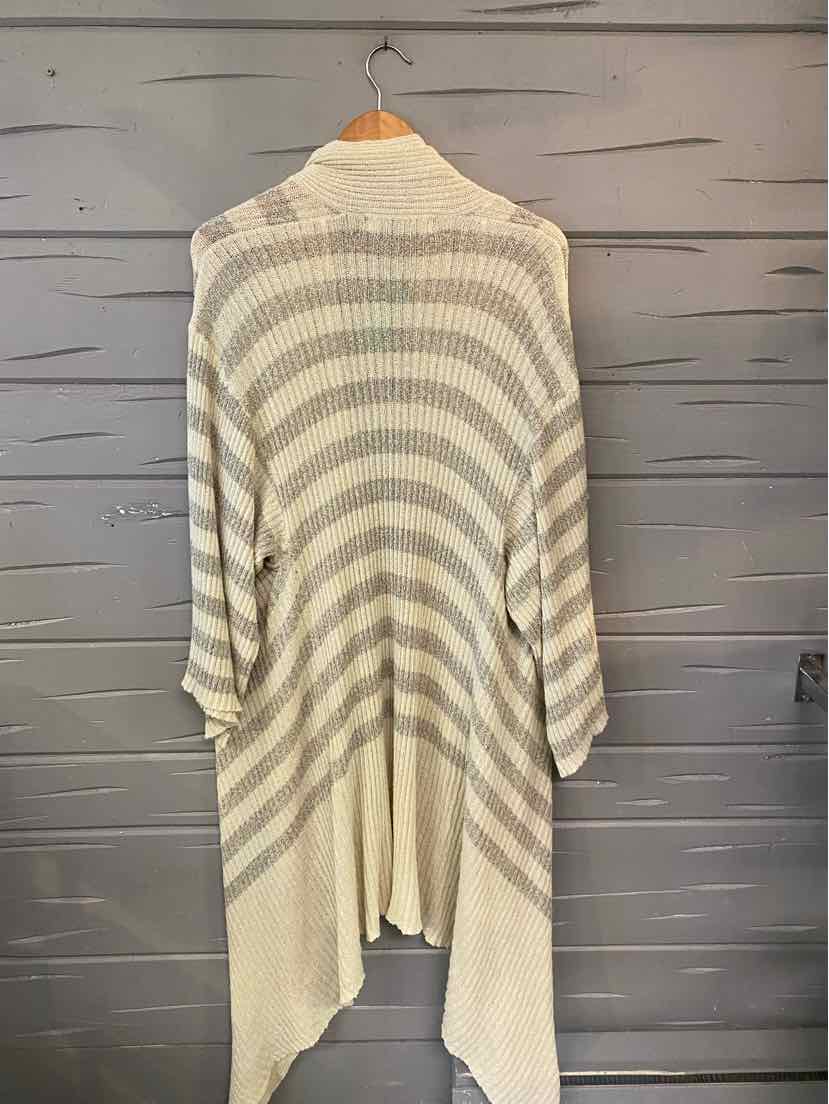 Light cream and beige striped knit cardigan with asymmetrical hem and long sleeves hanging on wooden hanger.