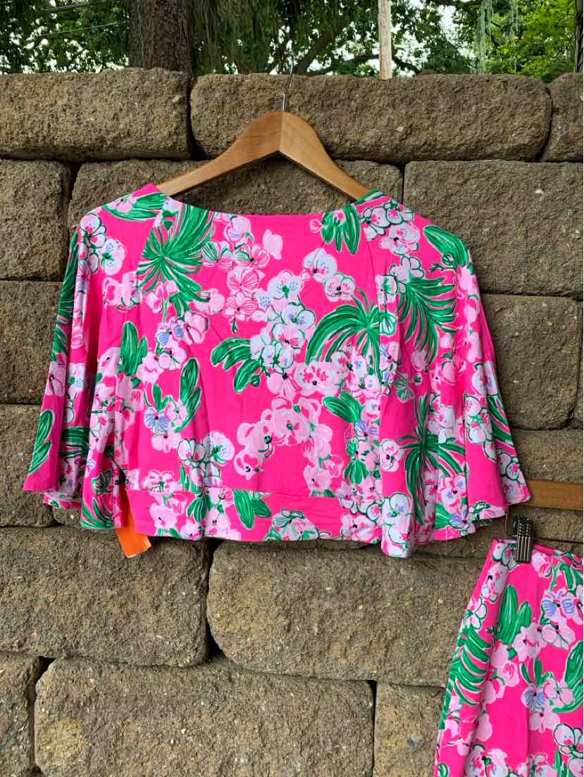 Bright pink cropped blouse with white and green tropical floral print, loose fit, three-quarter sleeves.