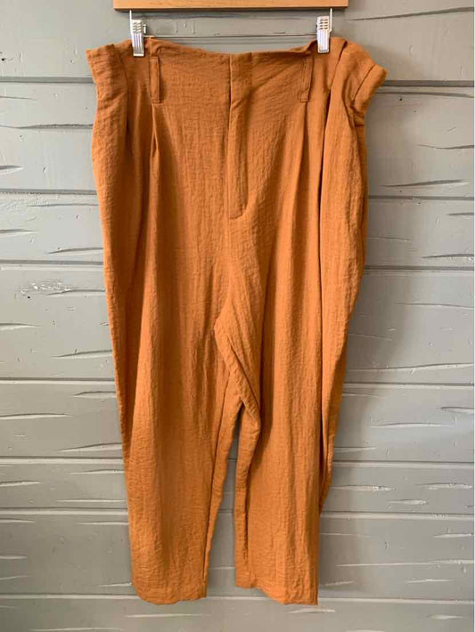 Plus-size burnt orange high-waist pants with a paperbag waist and textured fabric.
