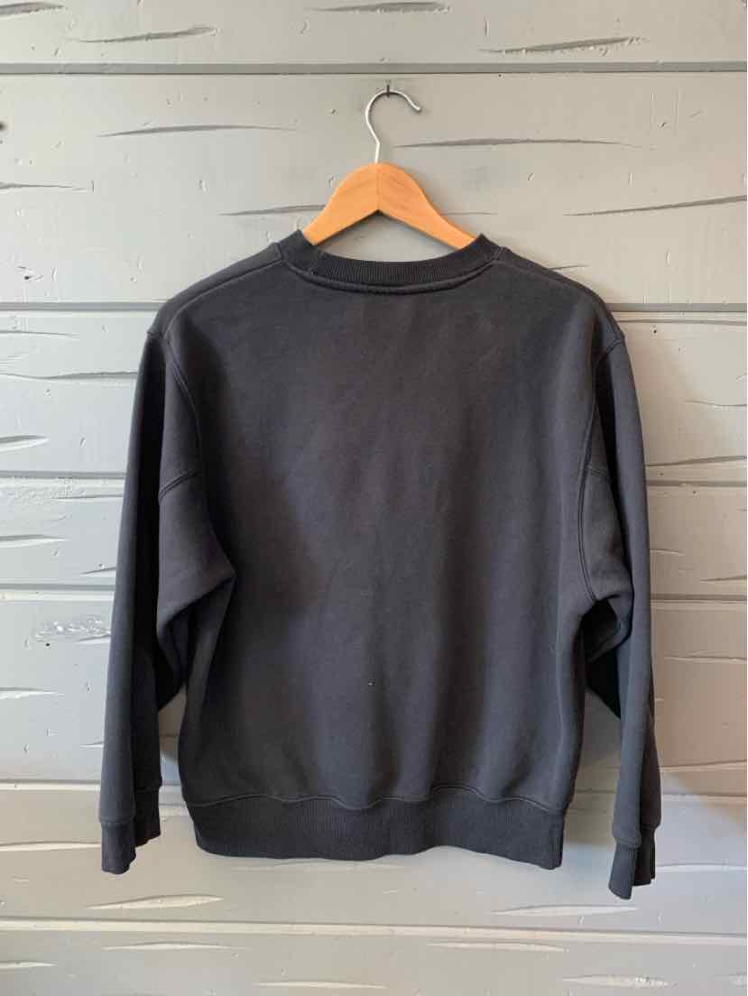 Black crewneck sweatshirt with long sleeves and relaxed fit on wooden hanger.