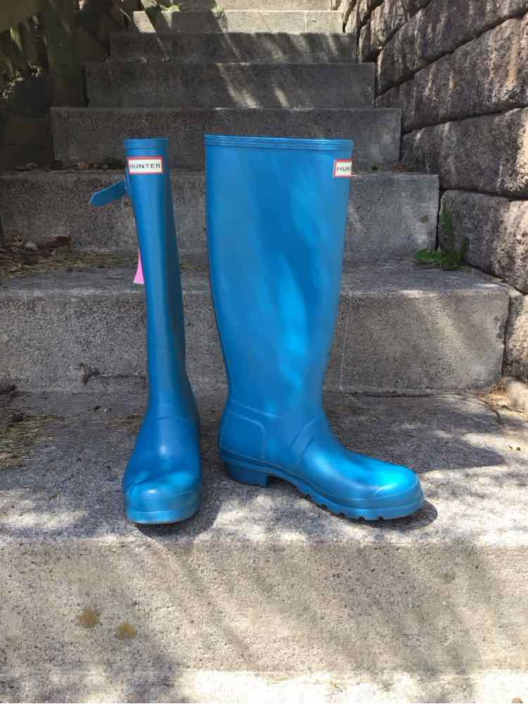 Tall blue rubber rain boots with rounded toes and branded labels near the top.