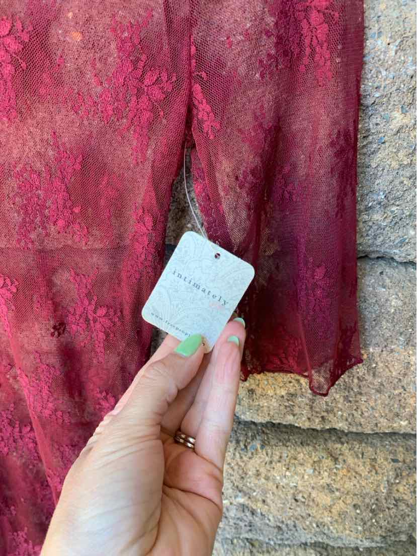 Burgundy lace fabric with floral pattern on sheer material, medium size tag held by hand with mint green nail polish.