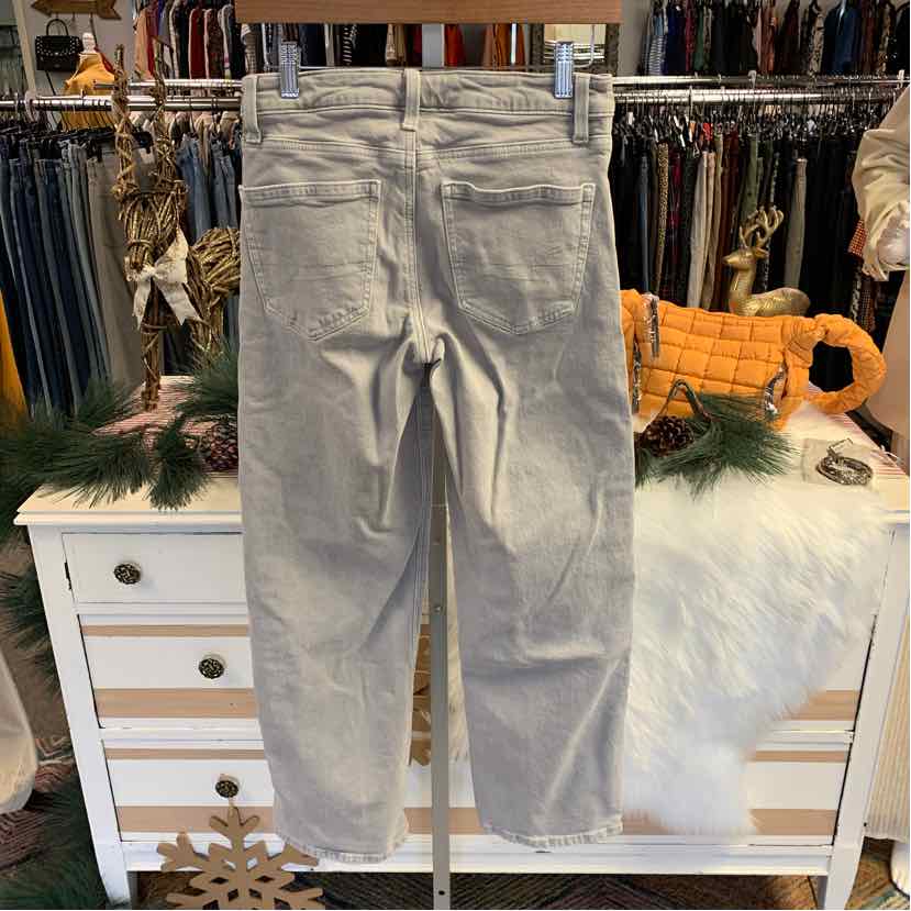 Light gray denim jeans with a straight leg and classic five-pocket design hanging on a wooden hanger.