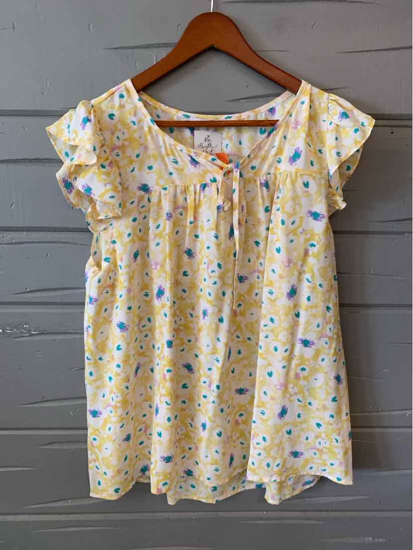 Light yellow floral blouse with short flutter sleeves and a square neckline on wooden hanger.