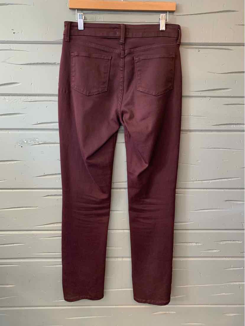 Burgundy slim-fit jeans with back pockets and belt loops hanging on wood hanger.