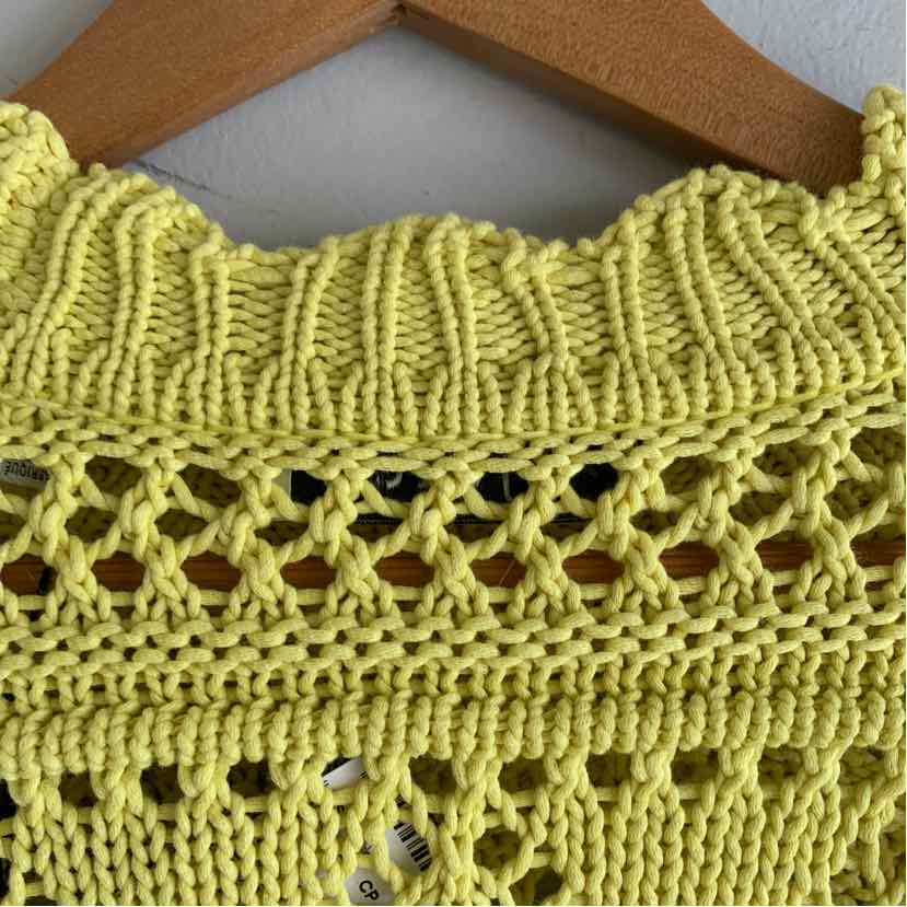 Yellow knitted fabric with openwork and ribbed texture on a wooden hanger.