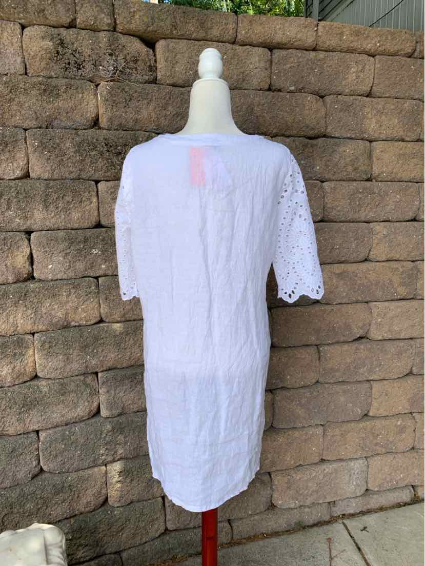 White knee-length dress with short eyelet sleeves and scalloped edges on a mannequin outdoors.