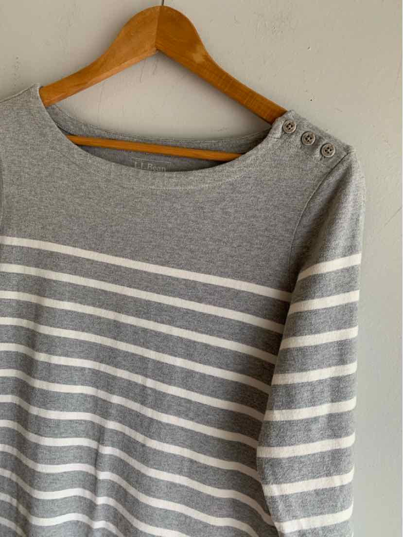 Gray and white striped long-sleeve sweater with three buttons on shoulder, hanging on wooden hanger.