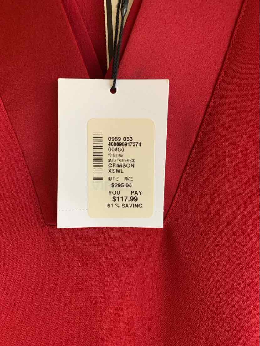 White rectangular price tag hanging on a red fabric garment with black string, showing product details and price $117.99.