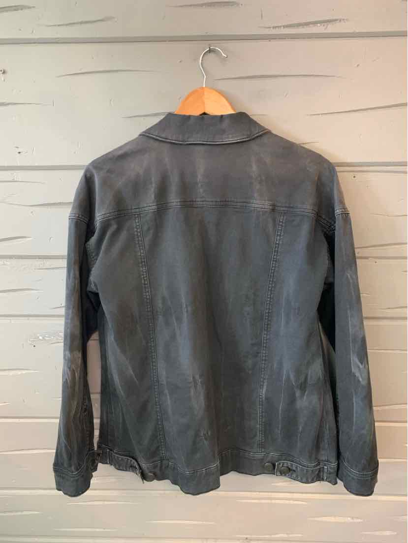 Black denim jacket with long sleeves and classic collar, hanging on wooden hanger against light gray wall.