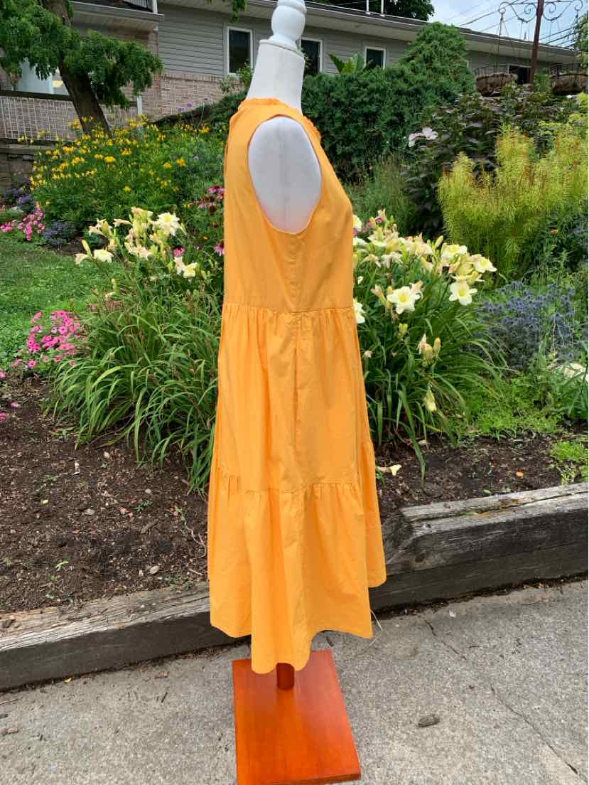 Bright orange sleeveless midi dress with tiered skirt and scoop neckline on mannequin.