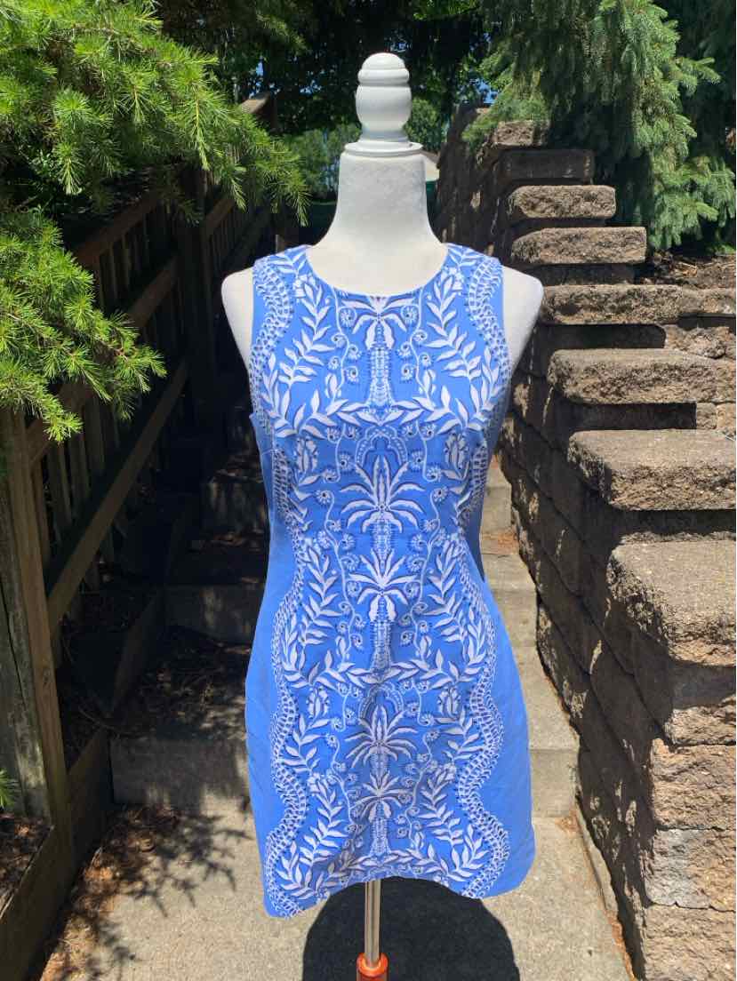 Sleeveless blue dress with white floral and leaf pattern, round neckline, knee-length, fitted silhouette.