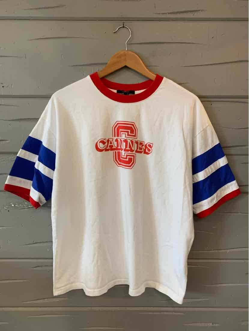 White short-sleeve t-shirt with red collar and sleeve cuffs, blue and white double stripes on sleeves, red "CAGINES" graphic