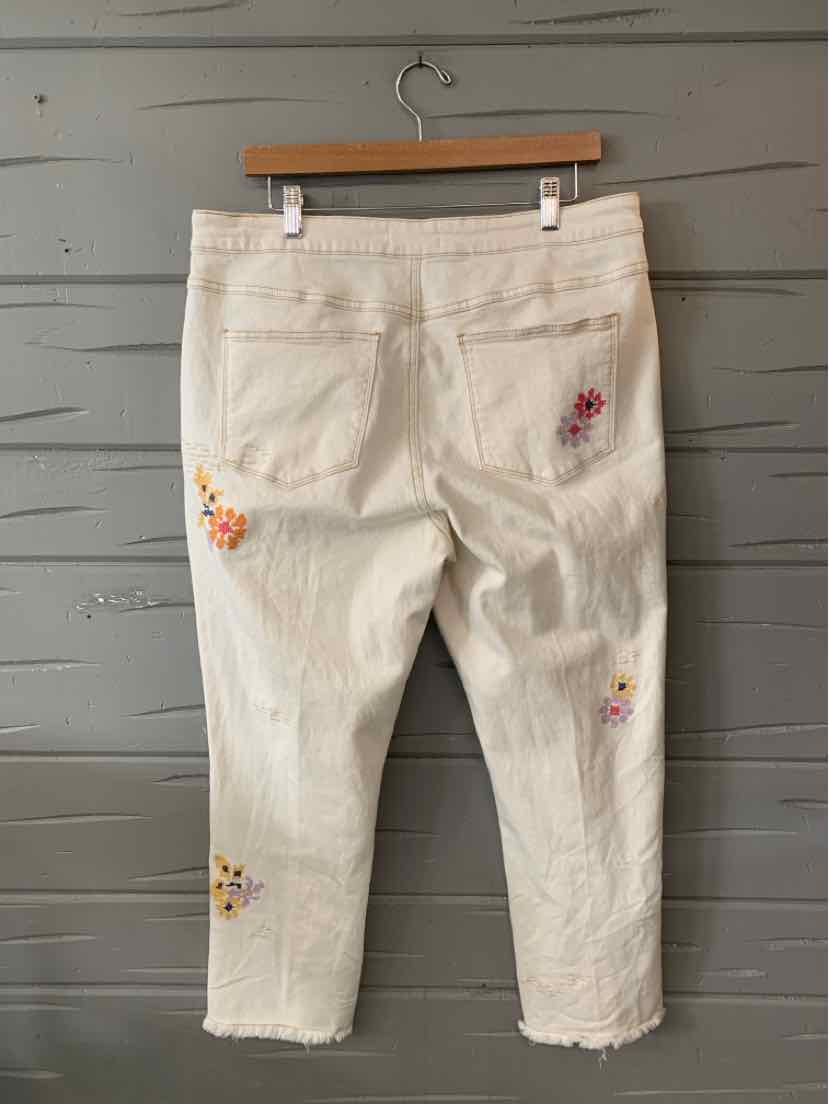 Cream-colored cropped jeans with colorful floral embroidery on pockets and legs.