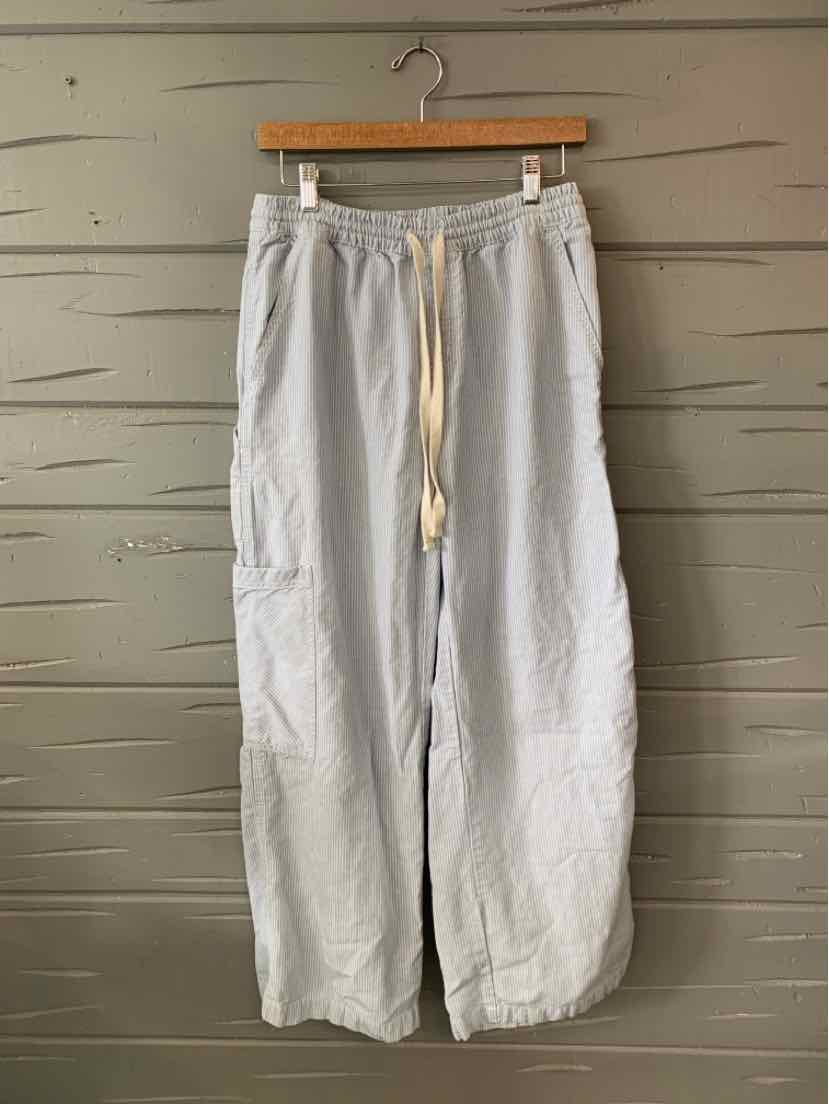 Light blue wide-leg pants with drawstring waist and relaxed fit hanging on wooden hanger.