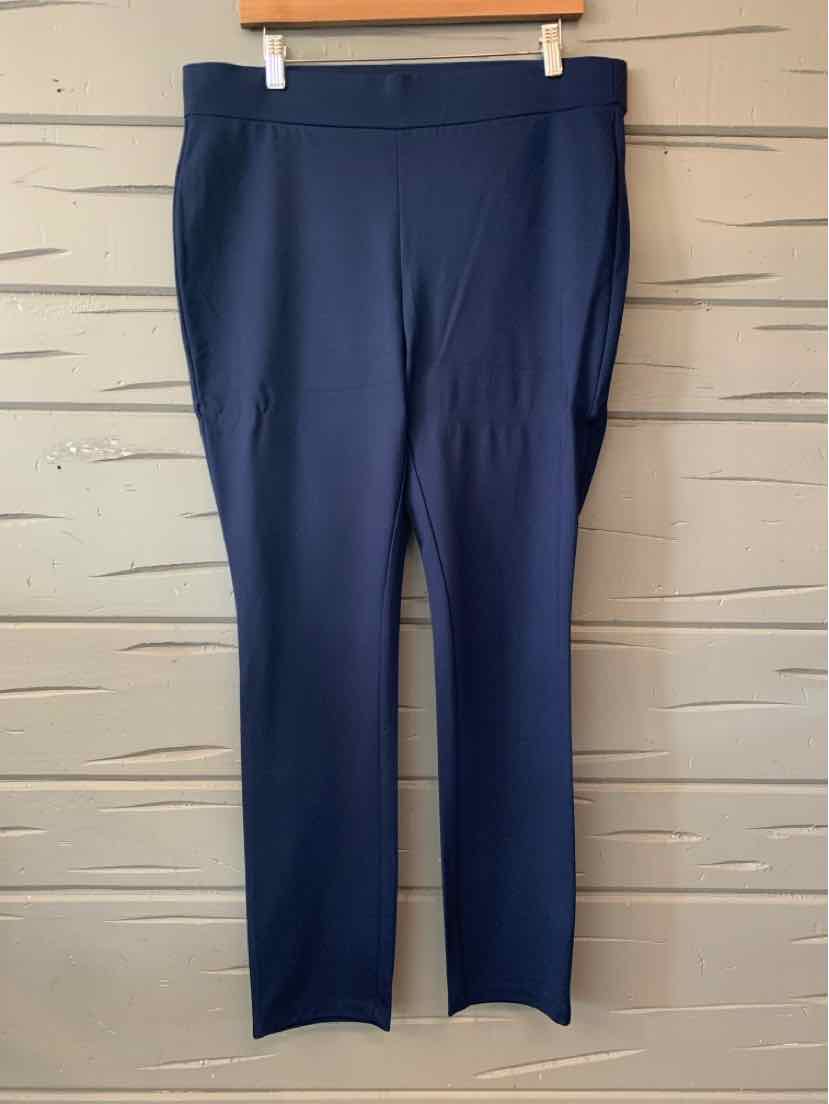 Dark navy NYDJ women's trousers with straight legs and a smooth waistband, hanging against a beige wall.