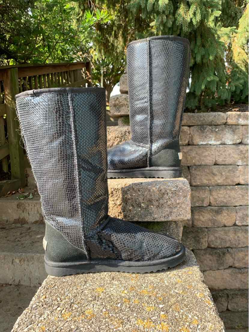 Black UGG tall boots with textured snake-print shafts, rounded toes, and flat soles.