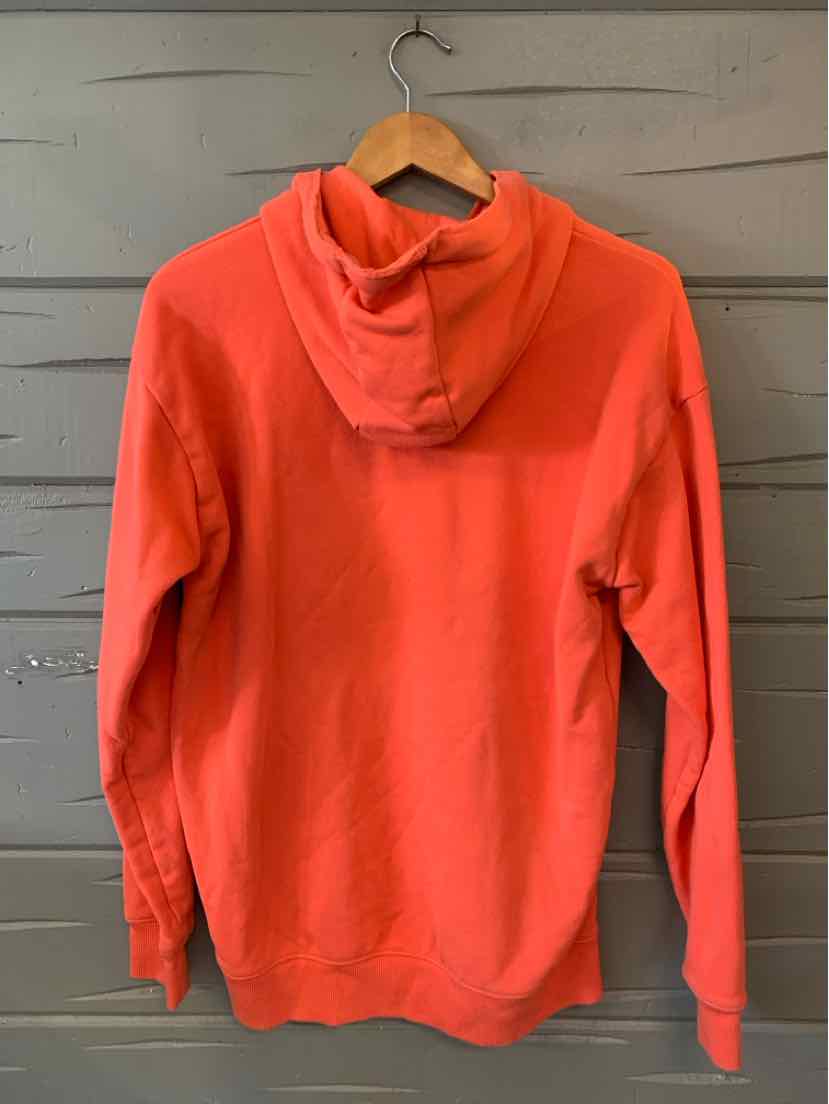 Coral orange hoodie with long sleeves and a hood, made from soft fabric, displayed on a wooden hanger.