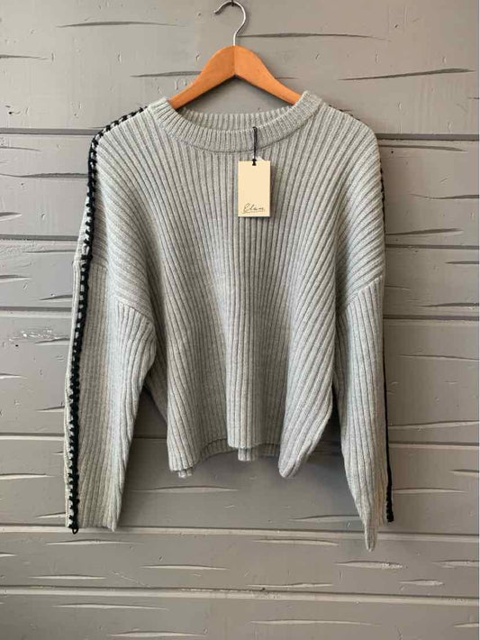 Light gray rib-knit sweater with black stripe detail on sleeves, crew neckline, and relaxed fit.