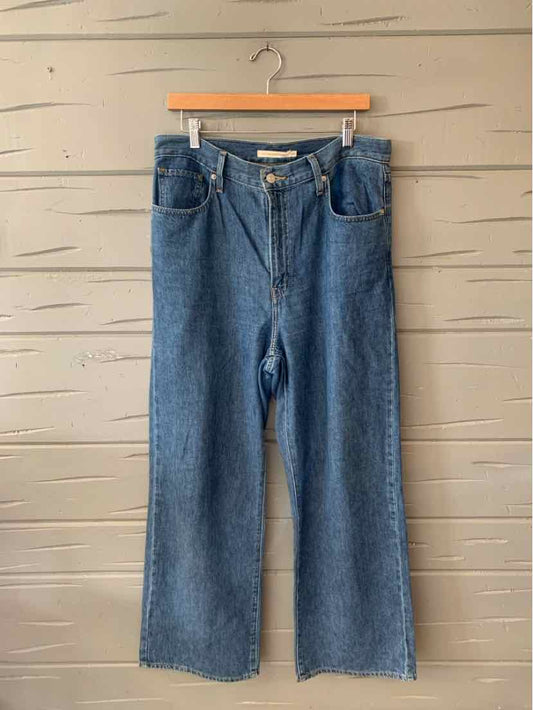 High-waisted blue denim jeans with wide legs, button and zipper closure, and front pockets.
