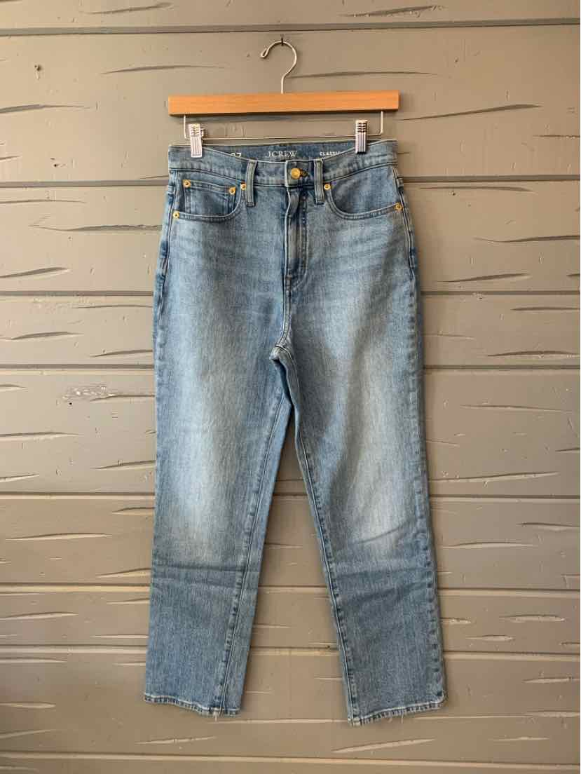 Light-wash blue J.Crew denim jeans with a straight-leg cut, displayed on a wooden hanger.