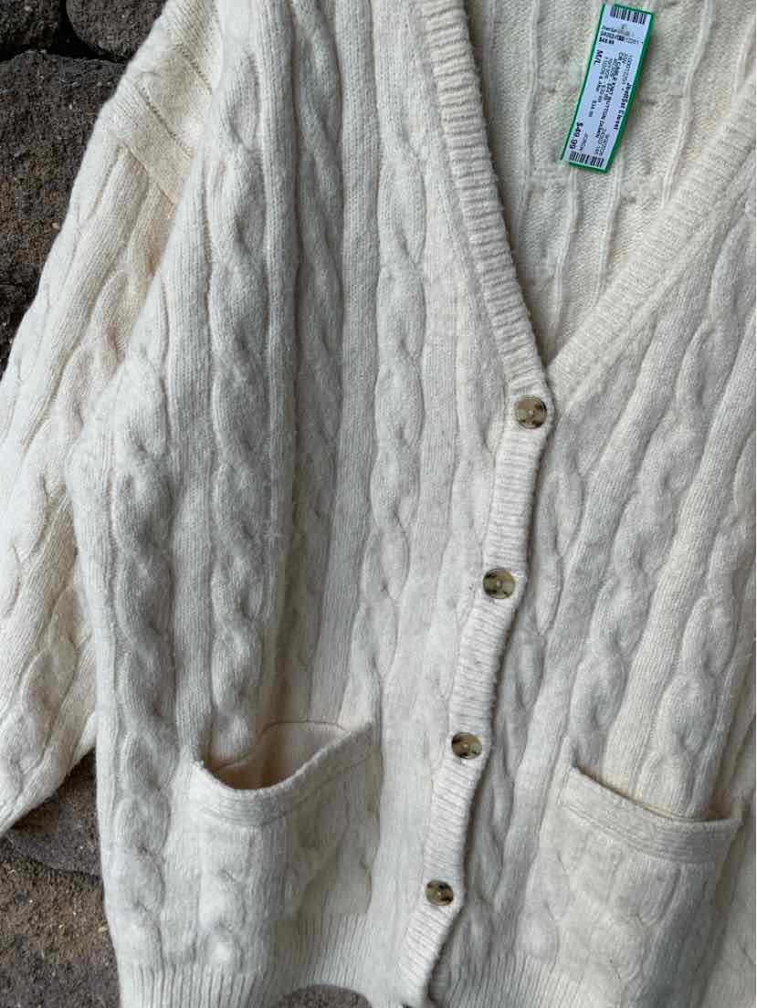 Cream cable knit cardigan sweater with v-neck, button front, and two front pockets.