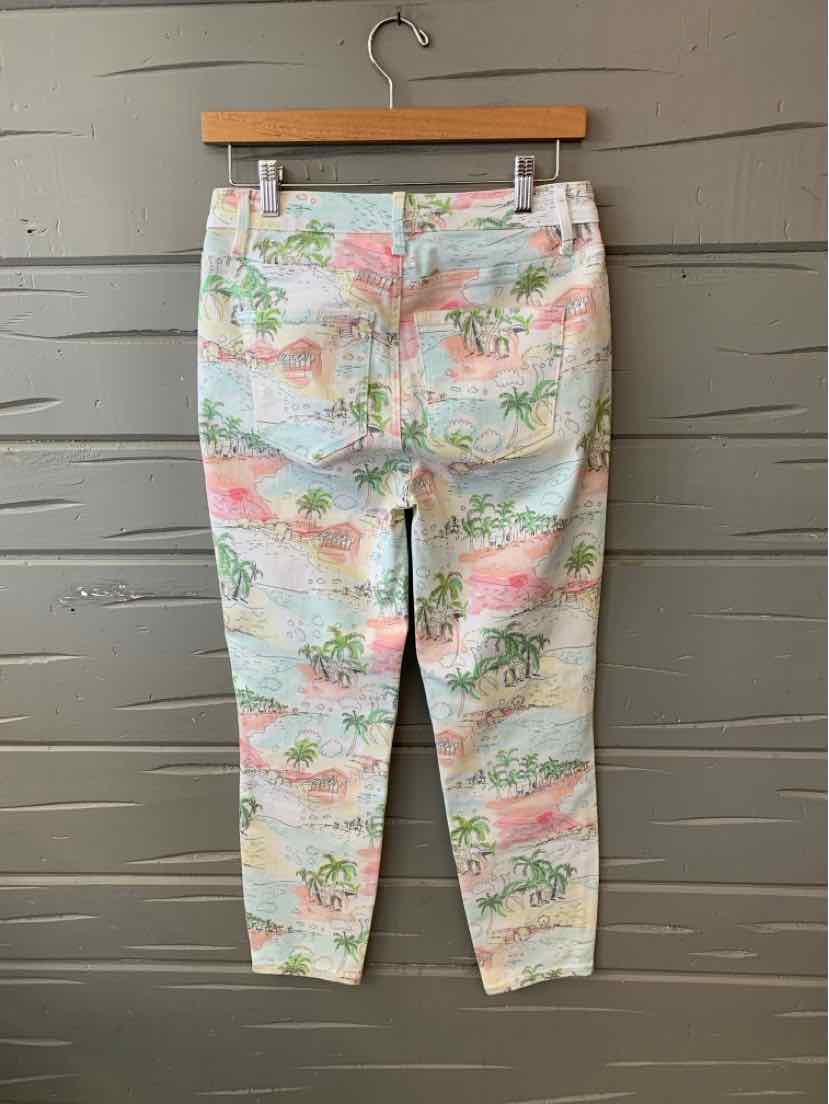 White cropped pants with pastel tropical floral print and back pockets hanging on wooden hanger.