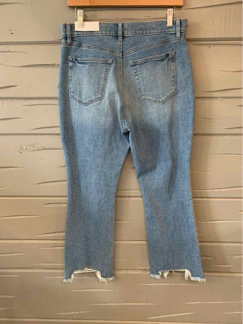 Light blue denim jeans with frayed hems and two back pockets hanging on a wooden hanger.