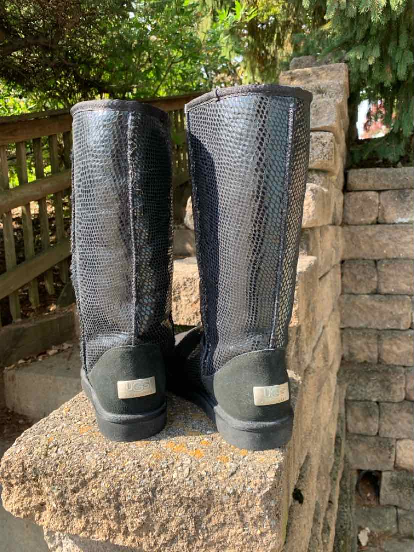 Pair of black UGG knee-high boots with textured snake-print panels, rounded toes, and light heel labels.