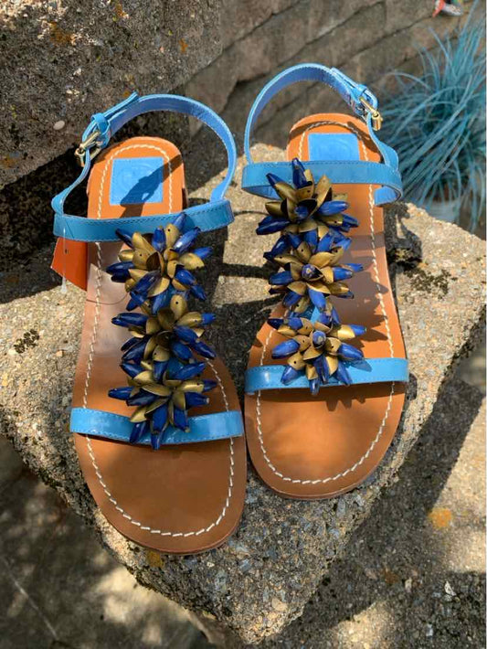Multi-color leather flat sandals with blue, orange, and brown straps, decorated with blue and gold flower embellishments.