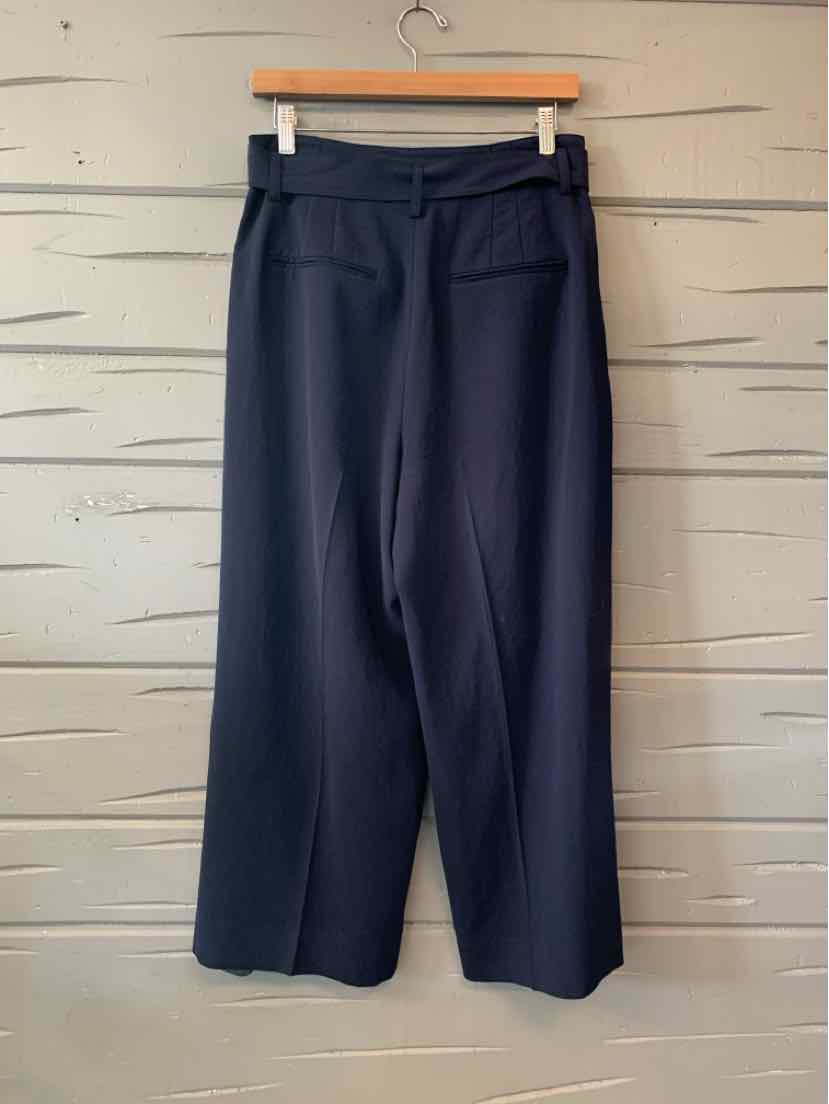 Navy blue Vince wide-leg trousers with a flat front, belt loops, and cropped hems, hanging on a wooden hanger.