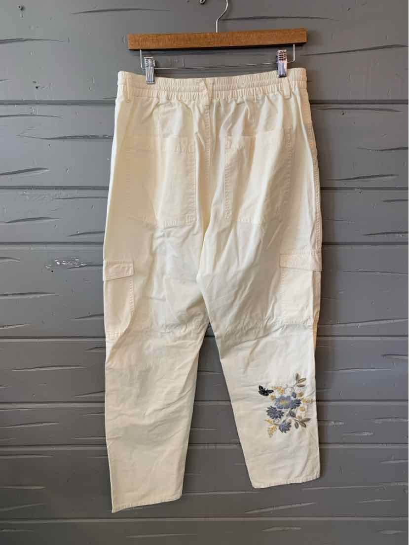 Cream-colored loose-fit pants with elastic waistband and floral embroidery on lower leg.