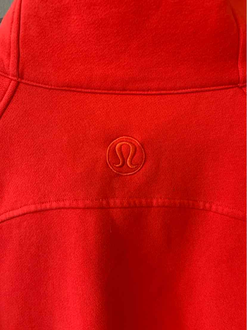 Bright red Lululemon athletic top with curved seam panels and an embroidered logo.