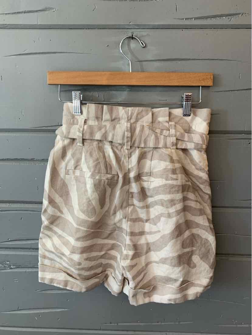 Beige and white zebra stripe high-waist shorts with belt loops on wooden hanger.