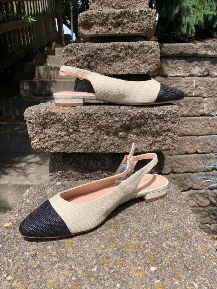 Tan and black color block slingback flat shoe with pointed toe and low heel.