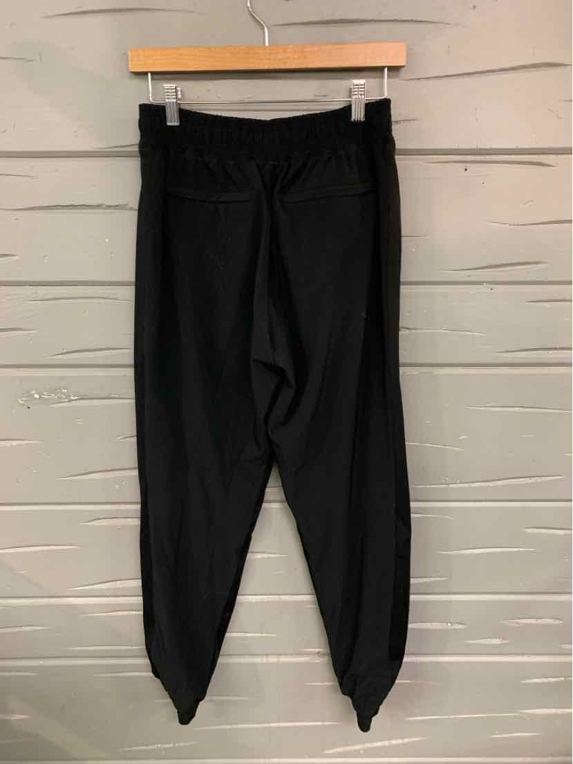 Black high-waisted leggings with gathered cuffs and smooth, stretchy fabric hanging on wooden hanger.