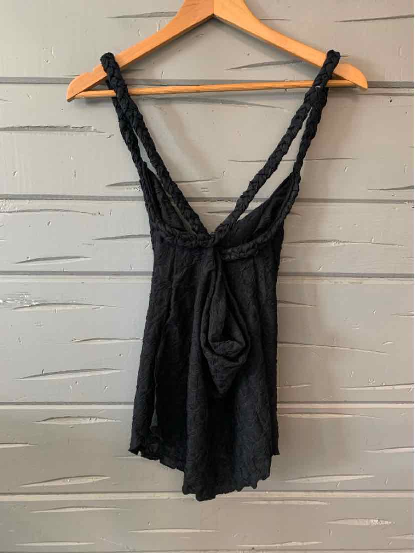 Black sleeveless romper with textured fabric and braided shoulder straps on wooden hanger.