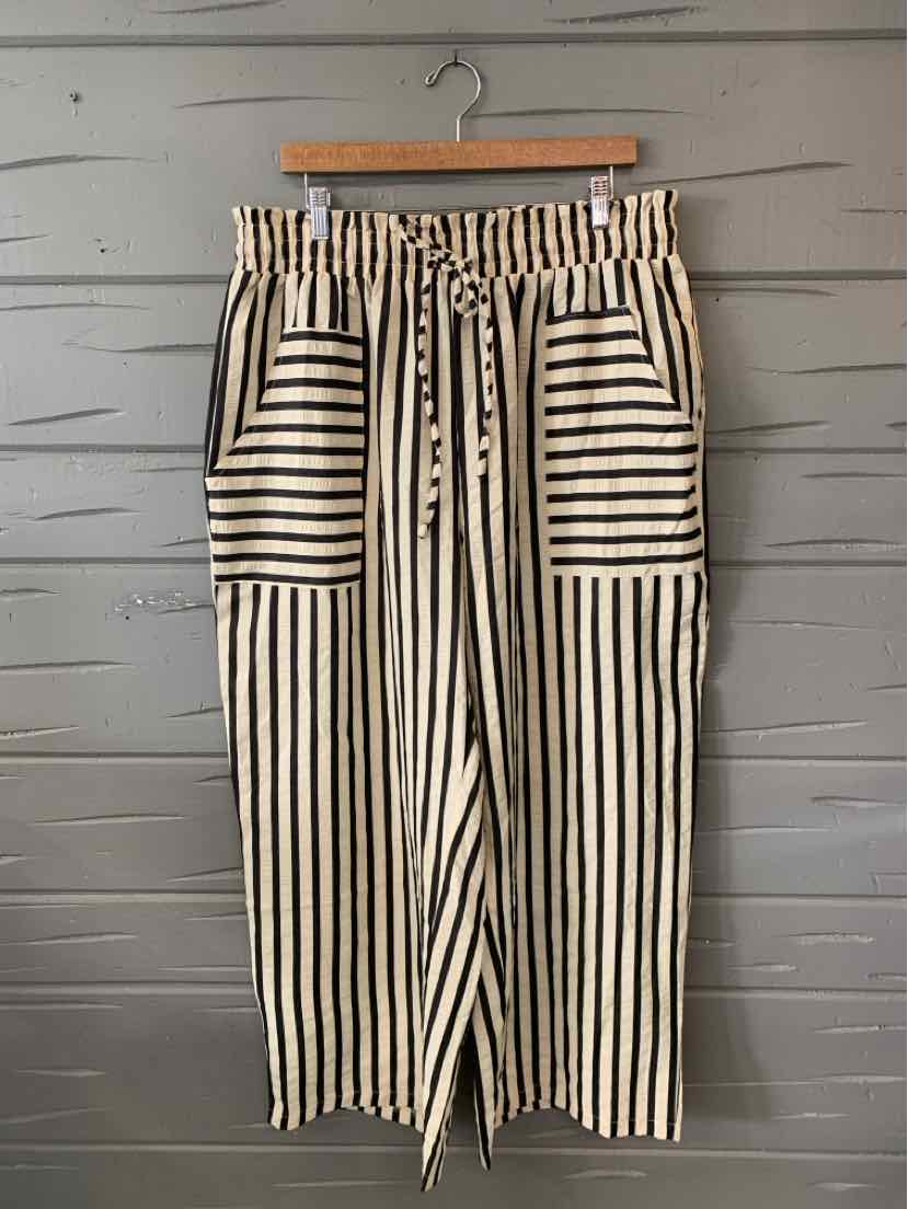 Tan wide-leg pants with vertical black stripes, elastic waistband, and large front pockets with horizontal stripes.