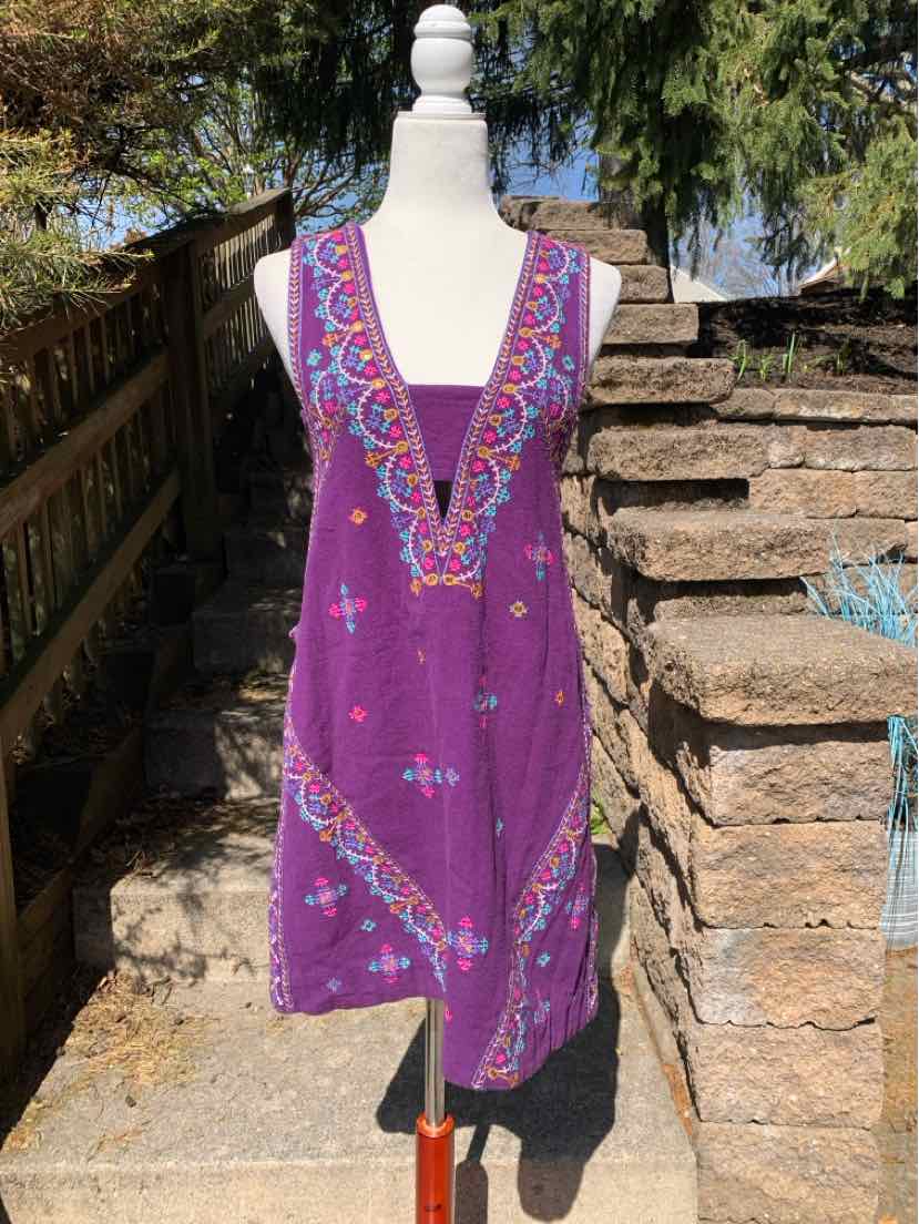 Purple sleeveless dress with intricate pink and blue embroidery on a white mannequin outdoors.