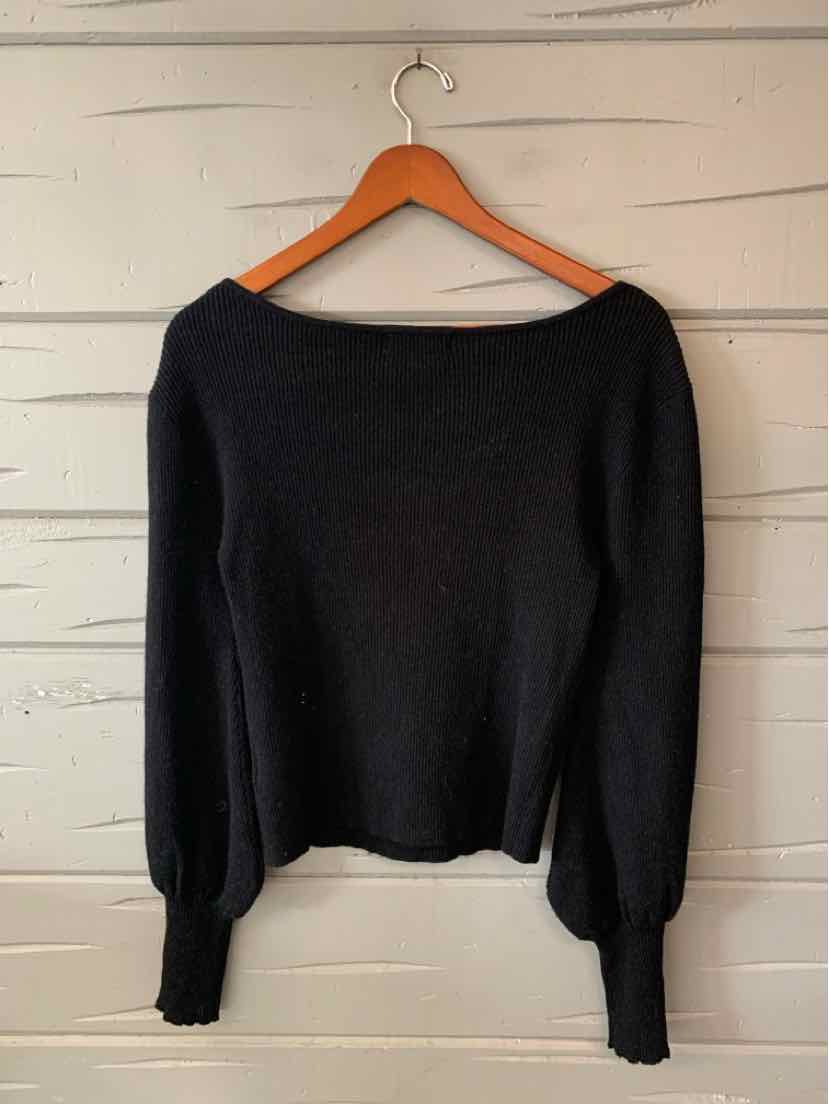 Black long-sleeve knit top with a wide boat neckline and gathered cuffs, hanging on a wooden hanger.