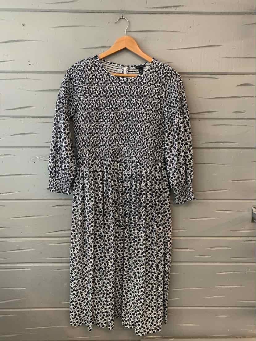 Black and white floral long-sleeve midi dress with gathered waist and round neckline.
