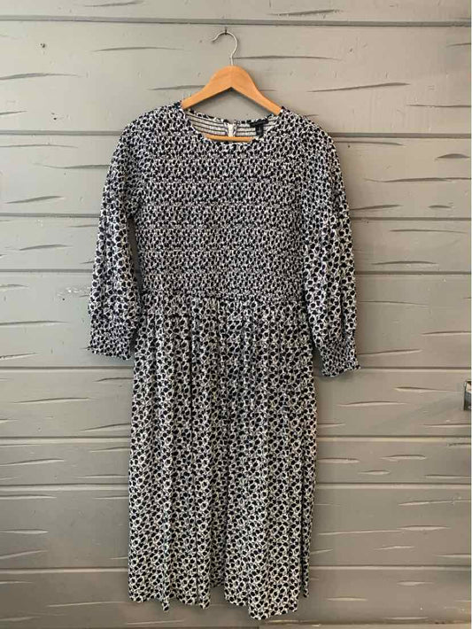 Black and white floral long-sleeve midi dress with gathered waist and round neckline.