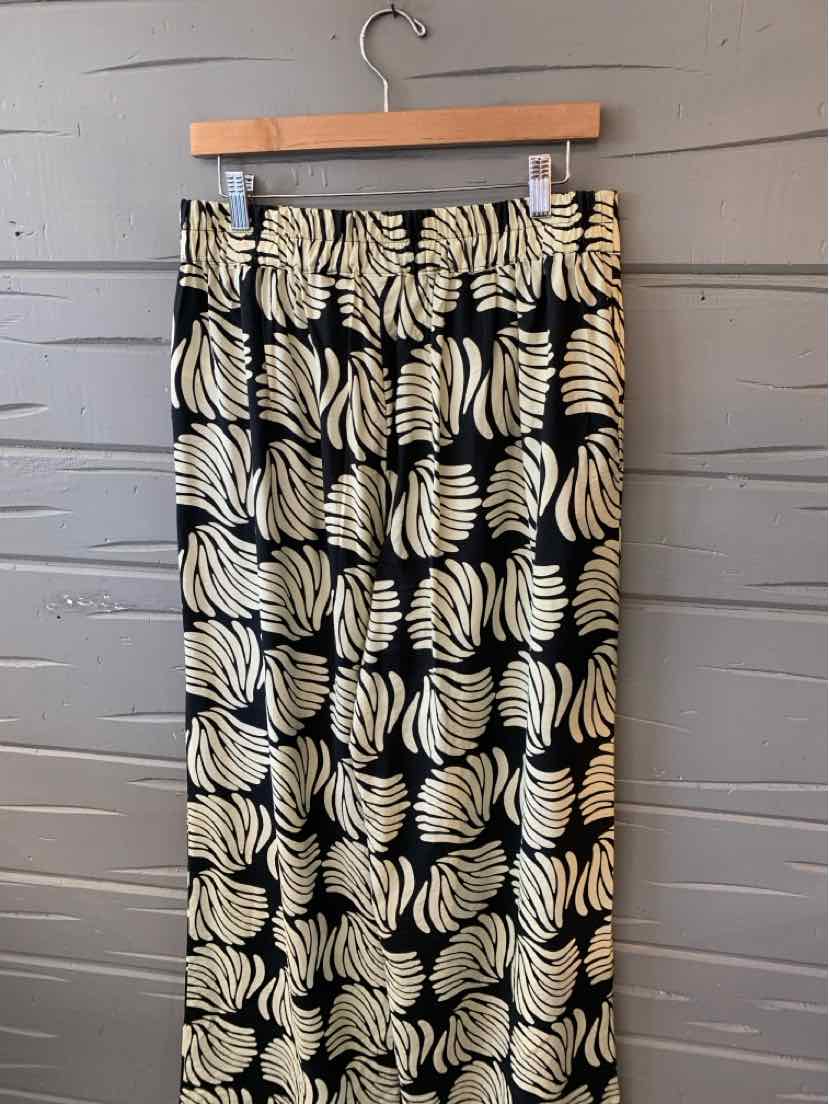 Black midi skirt with beige abstract leaf pattern and straight silhouette hanging on wooden hanger.