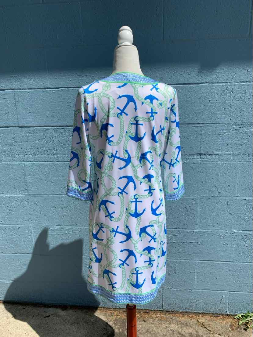 White knee-length dress with blue anchor patterns and 3/4 sleeves on a mannequin against a blue wall.