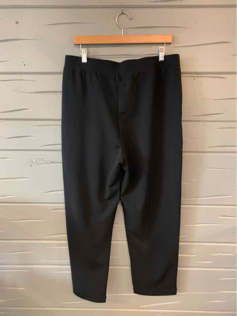 Black large loose-fit tapered pants with elastic waistband hanging on wood hanger.