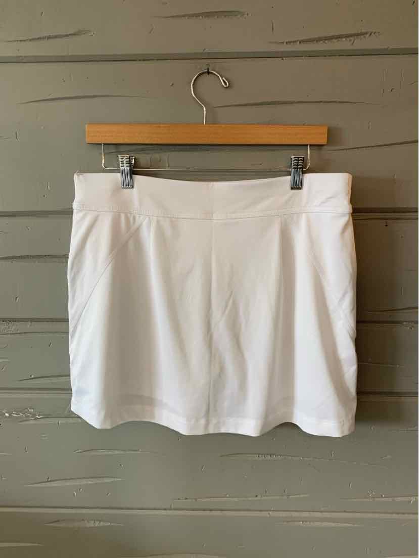 White Callaway golf skirt with a medium waistband and slight pleats at the front, hanging on a wooden hanger against a.