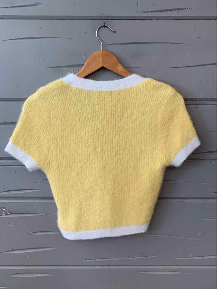 Yellow short-sleeve knit sweater with white ribbed collar, cuffs, and hem on wooden hanger.