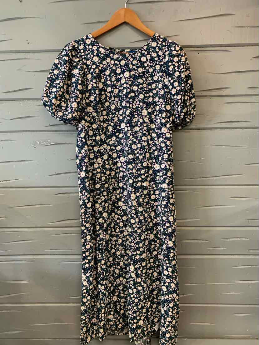 Navy blue floral dress with puff sleeves and midi length hanging on wooden hanger.